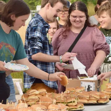 several standing students take sandwiches from platters