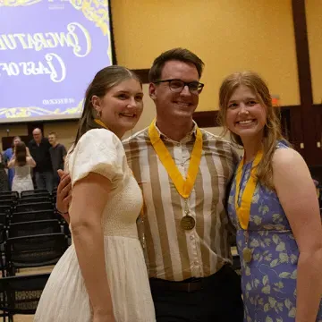 three students smile at graduation