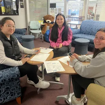 three female students sit around a table