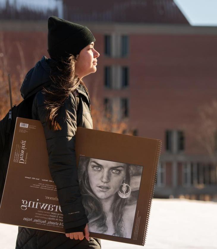 Student walking to class with drawing book